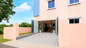 A modern hotel entrance with a glass door, a tiled walkway, and a well-maintained lawn. - Classic Bhubaneswar New Station Road (Bhubaneshwar)
