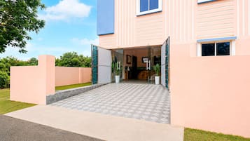A modern hotel entrance with a glass door, a tiled walkway, and a well-maintained lawn.