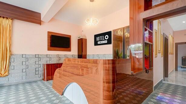 A hotel reception area with a wooden reception desk, a digital clock, and a sign indicating the hotel is serviced by OYO. - Classic Bhubaneswar New Station Road (Bhubaneshwar)