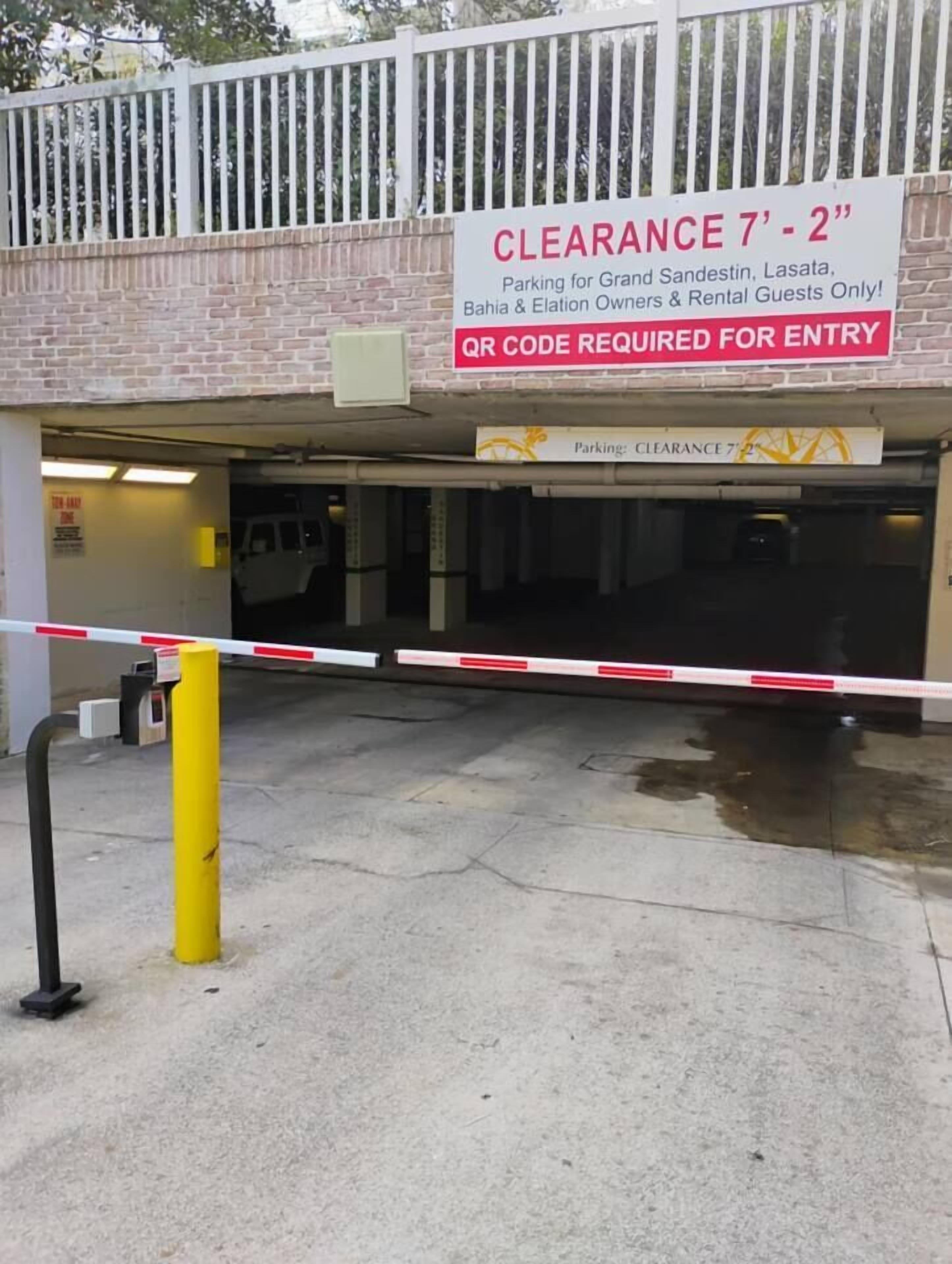A gated parking entrance with a height restriction sign and a QR code for entry.