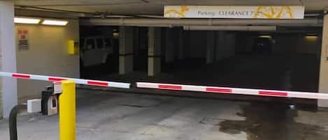 A gated parking entrance with a height restriction sign and a QR code for entry.