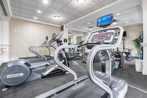 A gym with treadmills, elliptical machines, and a television screen. - Luxury Baytowne Wharf- Bahia Breeze -Pool View (Miramar Beach)