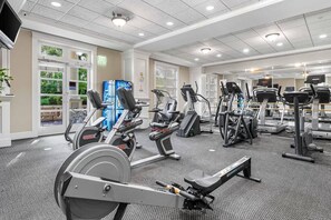 A gym with various exercise equipment, including treadmills and stationary bikes, and a large window providing natural light. - Luxury Baytowne Wharf- Bahia Breeze -Pool View (Miramar Beach)