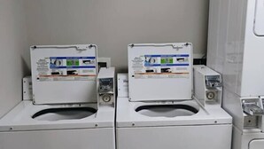 Zwei Waschmaschinen mit Frontlader, Bedienfeldern, einem weißen Gehäuse und einem roten Boden.