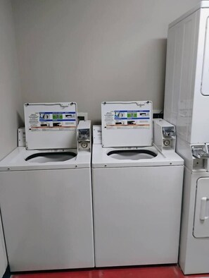 Two front-loading washing machines with control panels, a white cabinet, and a red floor. - Luxury Baytowne Wharf- Bahia Breeze -Pool View (Miramar Beach)