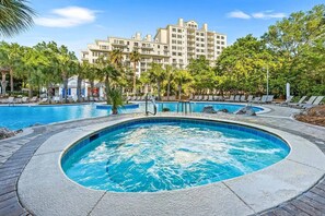 A hotel with a large swimming pool, lounge chairs, and palm trees. - Luxury Baytowne Wharf- Bahia Breeze -Pool View (Miramar Beach)