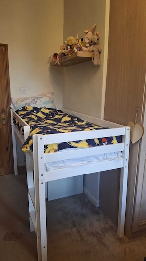 Ein Stockbett mit Pokémon-Motiv, ein Regal mit Kuscheltieren und eine herzförmige Dekoration an der Wand.