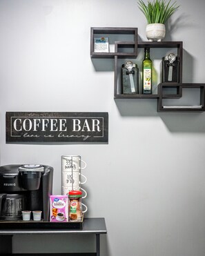 Ein Café-Bereich mit einem Schild, auf dem 'COFFEE BAR love is brewing' steht, einer Keurig-Kaffeemaschine, einem Kaffeeautomaten und verschiedenen Kaffeeprodukten.
