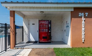 Eine Coca-Cola-Getränkeautomaten vor einem Gebäude mit einem Schild, auf dem '247 LAUNDRY' steht.