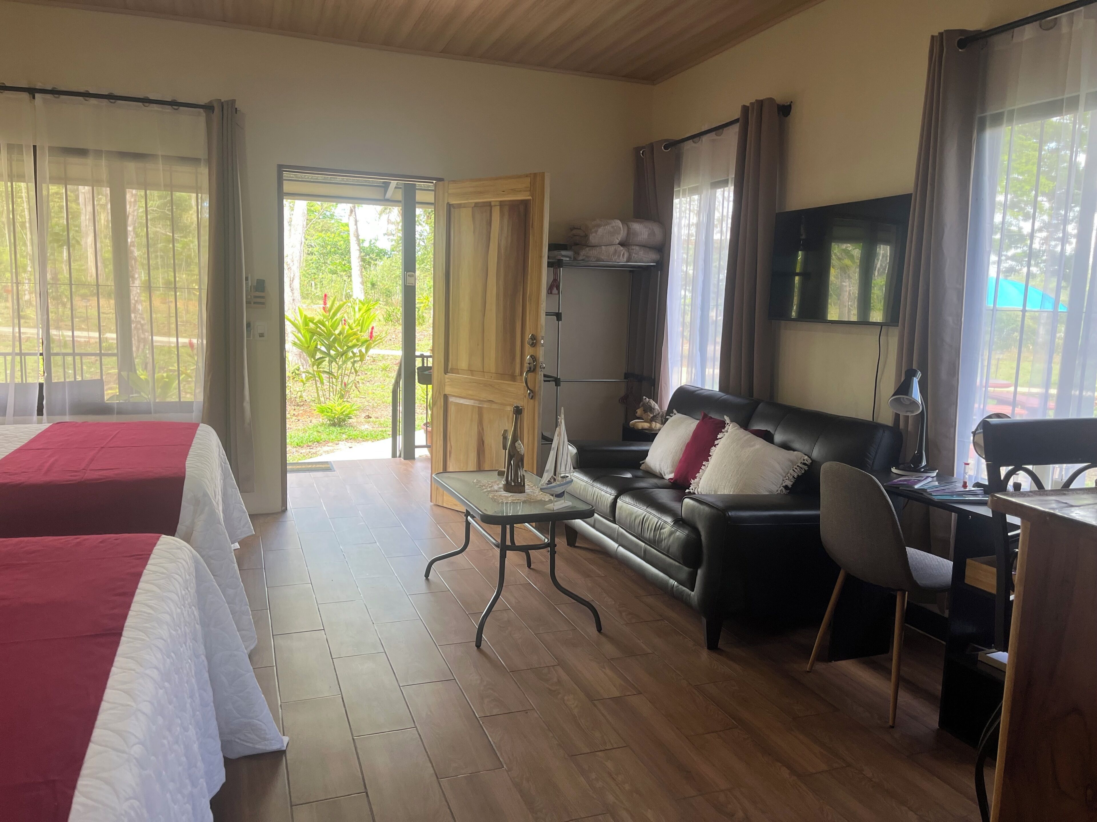 Ein Hotelzimmer mit zwei Betten, einem Sofa, einem Schreibtisch und einem Fernseher.