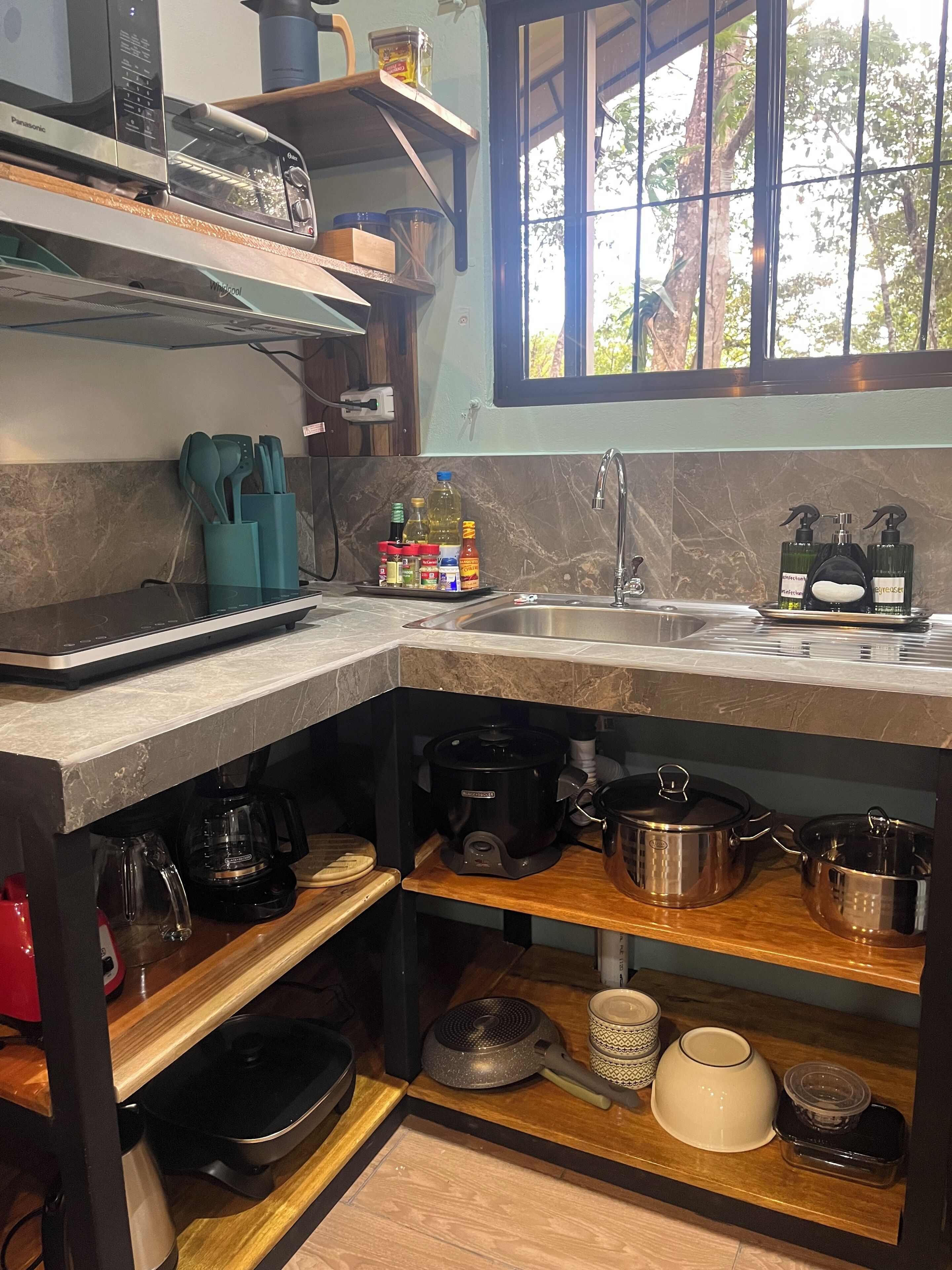 A compact kitchen with a built-in oven, a coffee maker, and a sink.