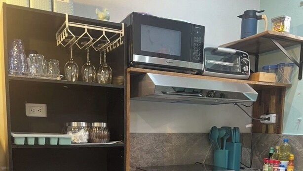 A compact kitchen with a microwave, toaster, and various kitchen utensils.