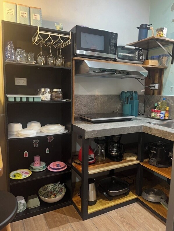 A compact kitchen with a microwave, toaster, and various kitchen utensils.