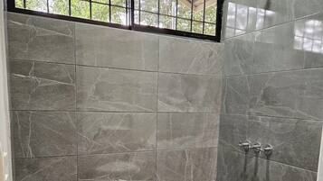 Un baño con ducha, paredes de azulejos y una ventana.