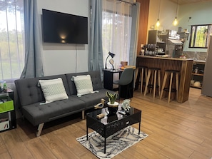 A modern living room with a sofa, coffee table, and a TV mounted on the wall.