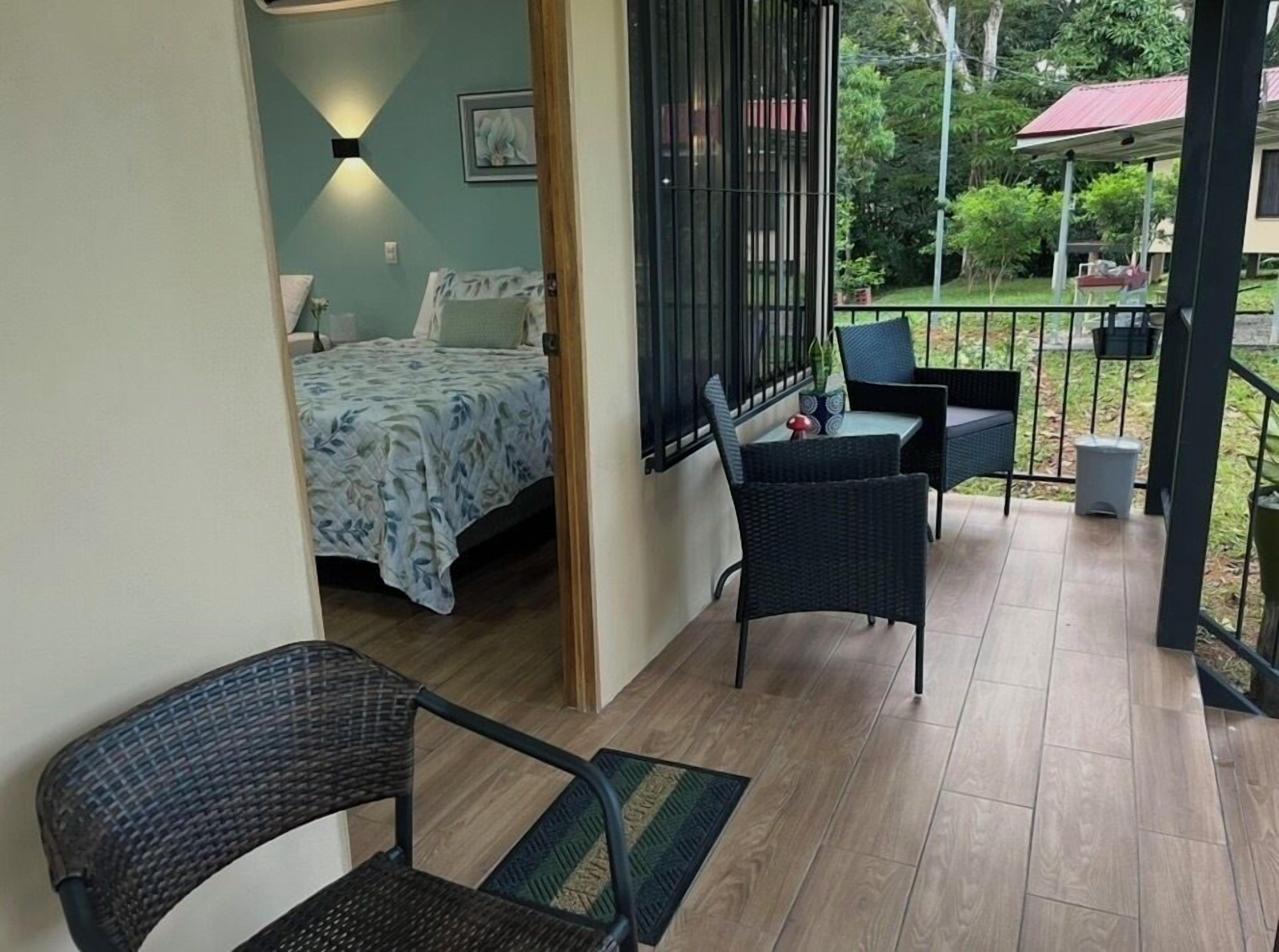 A bedroom with a bed, a nightstand, a chair, and a window with a view of the outdoors.