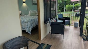 A bedroom with a bed, a nightstand, a chair, and a window with a view of the outdoors.