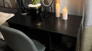 A desk with a lamp, a potted plant, a mirror, and candles.