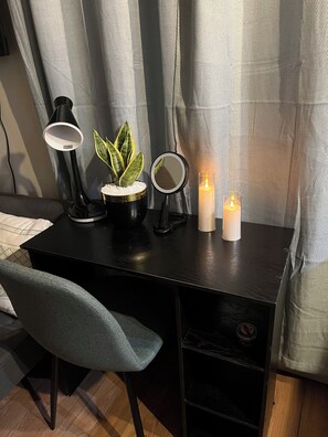 A desk with a lamp, a potted plant, a mirror, and candles.