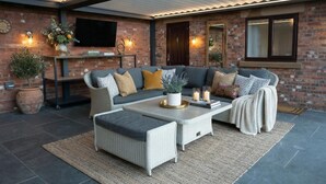 Uma área externa moderna com área de estar, sofás, mesa de centro e objetos decorativos.