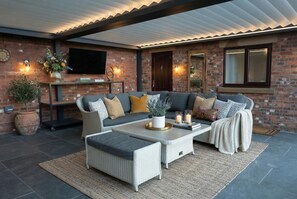A modern outdoor living area with a sofa set, a coffee table, and decorative items. - Country Retreat, Barn with Annexe - Large enclosed garden with countryside views (Wrexham)
