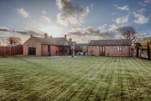 A brick house with a large lawn and a clear sky.