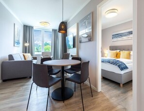Ein modernes Hotelzimmer mit Essbereich, einer Couch, einem Bett und Kunstwerken an den Wänden.