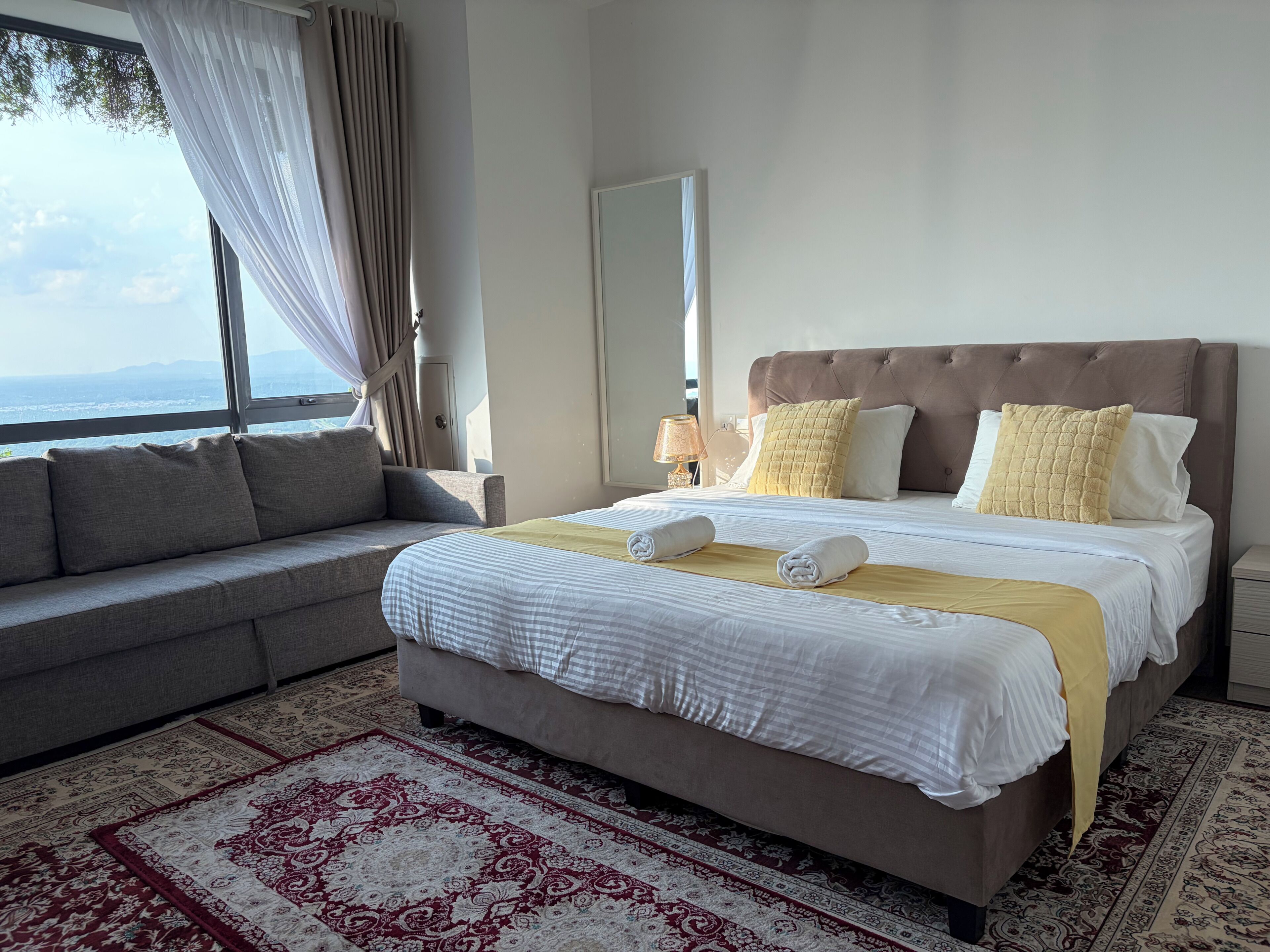 Une chambre d’hôtel avec un grand lit, un canapé, une table de chevet et une vue sur l’extérieur.