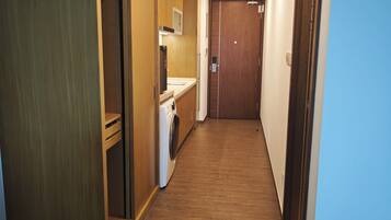 A hallway with wooden flooring, a washing machine, and a microwave.