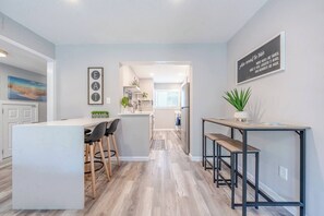 A modern kitchen with a central island, bar stools, and a dining area. - Private Gulf Beach 3BR Townhome | Pools & Tennis (Destin)