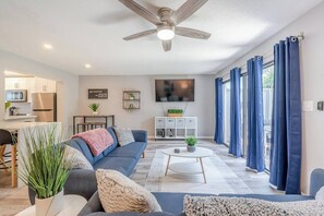 A modern living room with a sofa, coffee table, and a ceiling fan. - Modern Serenity - Destin Private Beach Access (Destin)