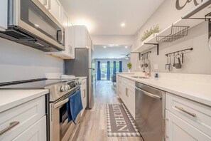 A modern kitchen with white cabinetry, stainless steel appliances, and a kitchen mat. - Modern Serenity - Destin Private Beach Access (Destin)