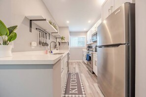 Une cuisine moderne dotée d’un réfrigérateur en acier inoxydable, de meubles blancs et d’un îlot central.