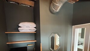Et værelse med et skrivebord, stol, reoler og et spejl.