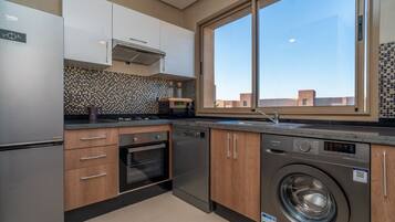 A modern kitchen with a built-in washer, a large window, and a tiled backsplash.
