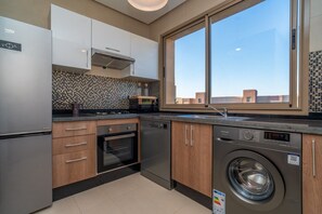 A modern kitchen with a built-in washer, a large window, and a tiled backsplash. - Prestigia Golf |Luxury 3BR| Pool&Atlas view (Marrakesh)