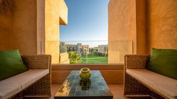 A balcony with wicker furniture and a tiled table, overlooking a residential area.