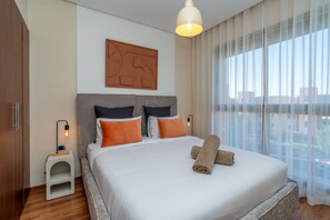 A neatly made bed with pillows, a bedside table with a lamp, and a large window with curtains. - Prestigia Golf |Luxury 3BR| Pool&Atlas view (Marrakesh)