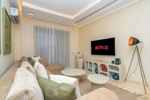 A modern living room with a sofa, two coffee tables, a TV mounted on the wall, and a lamp. - Prestigia Golf |Luxury 3BR| Pool&Atlas view (Marrakesh)