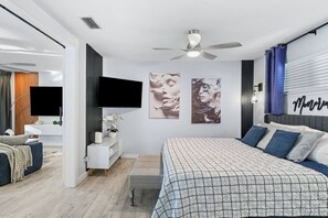 A modern bedroom with a large bed, a flat-screen TV, a ceiling fan, and artwork on the walls. - Modern Memories - Peaceful Lakeside View (Destin)