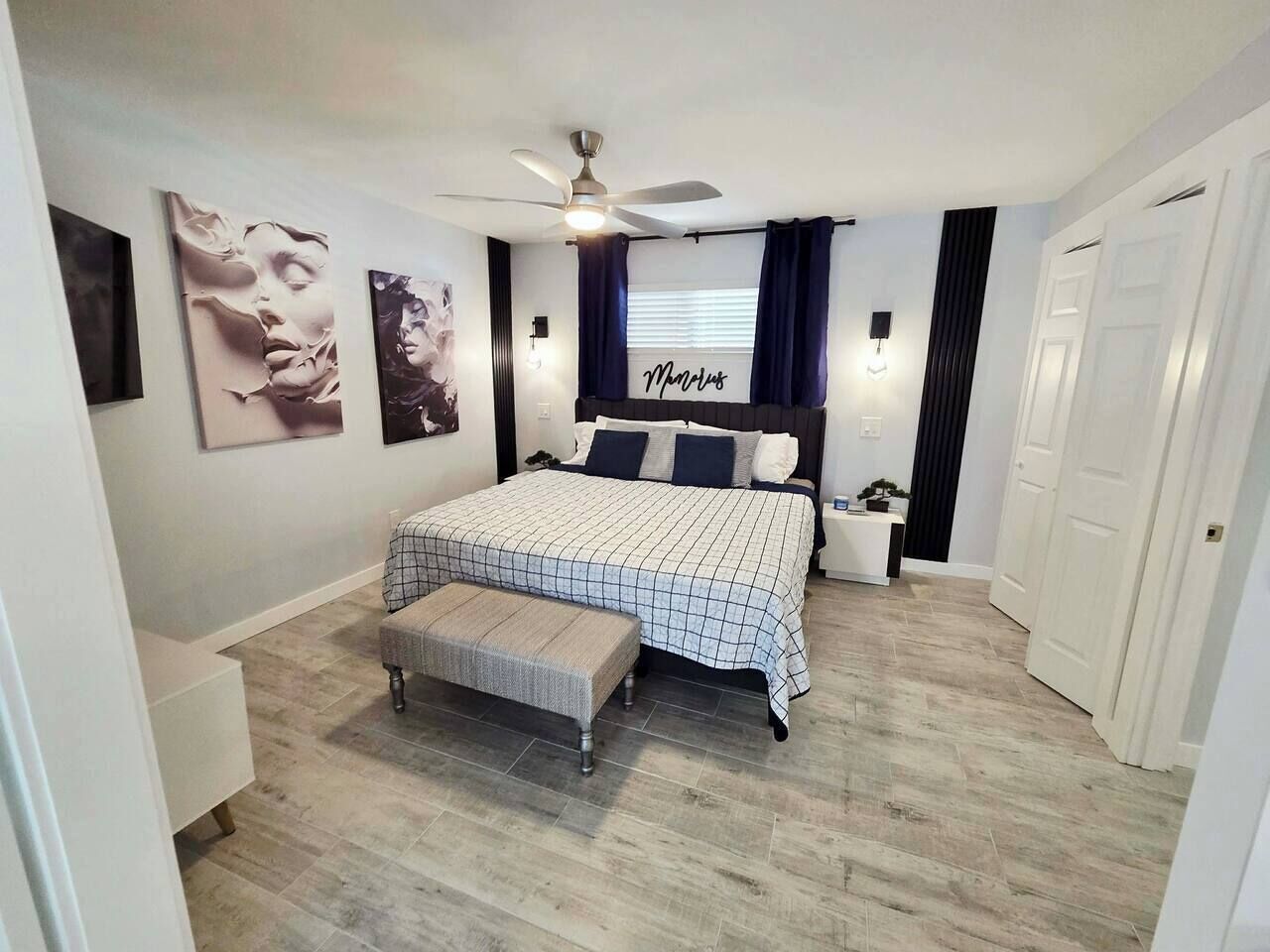 Ein Schlafzimmer mit Bett, einer Bank, einem Deckenventilator und Bildern an den Wänden.