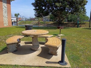 An outdoor seating area with a stone table and benches. - Modern Memories - Peaceful Lakeside View (Destin)