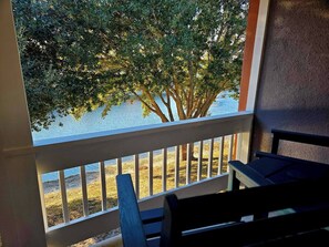 Un balcon donnant sur un arbre et une étendue d’eau.
