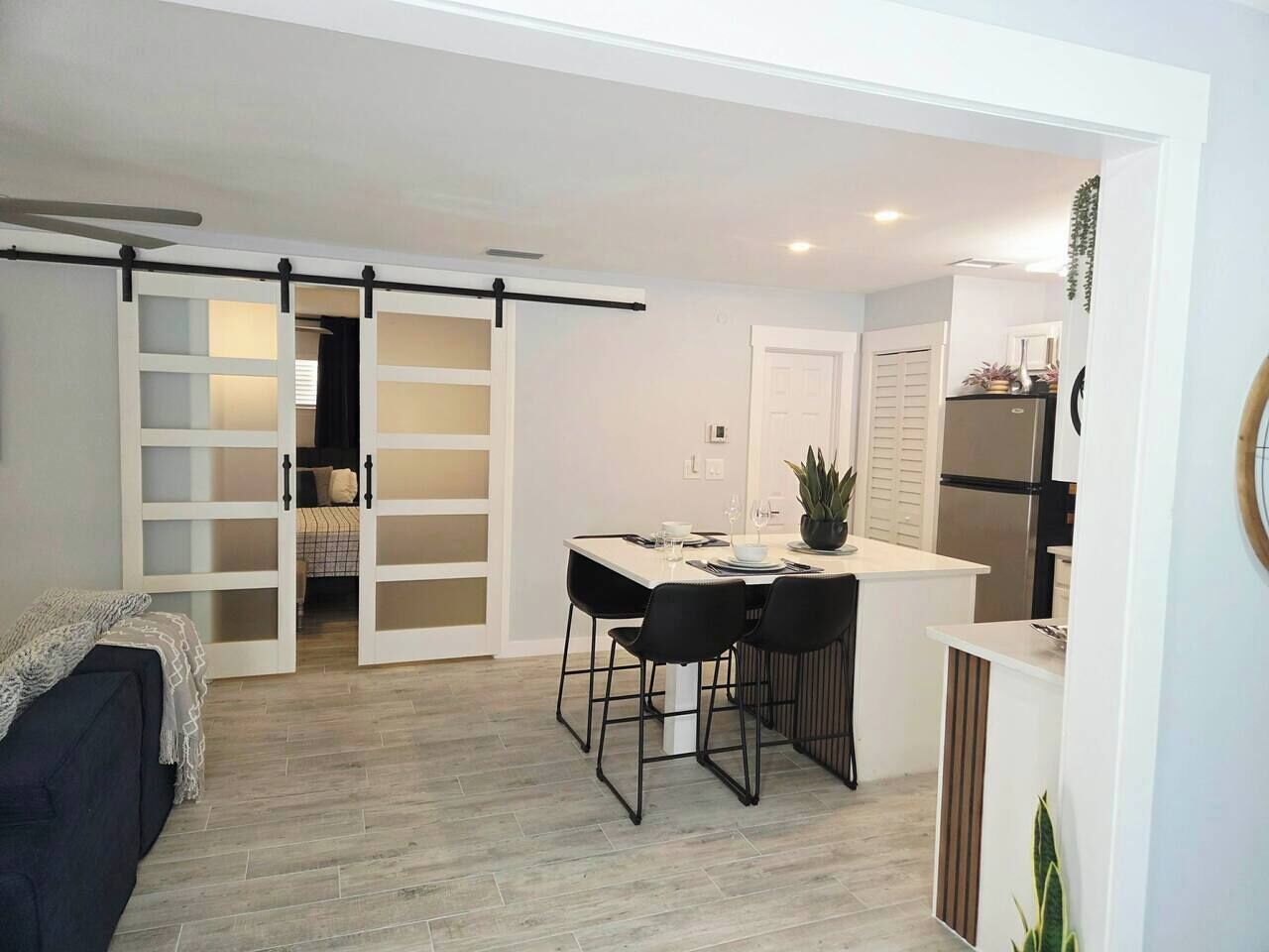 A compact living space with a dining area, kitchenette, and a sliding door leading to a bedroom.