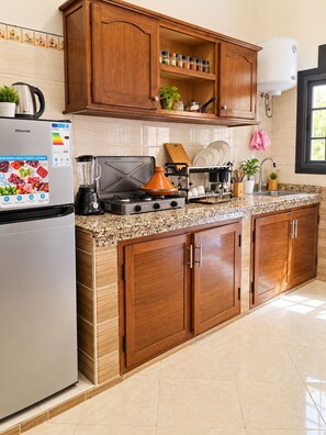 A kitchen with a Hisense refrigerator, a stove, a sink, wooden cabinets, and a window.