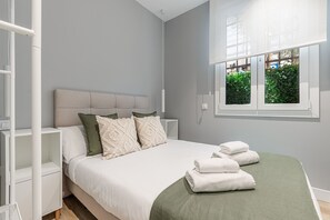 Une chambre à coucher avec un lit, des oreillers, une table de chevet, une fenêtre donnant sur un paysage verdoyant et une pile de serviettes.