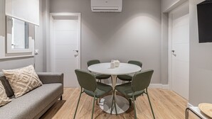 A room with a round table, four chairs, a sofa, and a window. - Waou Essence I Salamanca - Short-Term (Madrid)