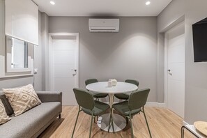A room with a round table, four chairs, a sofa, and a window. - Waou Essence I Salamanca - Short-Term (Madrid)