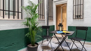 A small outdoor seating area with a table and chairs, a potted plant, and a door leading to a room. - Waou Essence I Salamanca - Short-Term (Madrid)