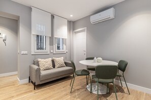 A modern living room with a grey sofa, a round table, and green chairs. - Waou Essence I Salamanca - Short-Term Rental (Madrid)